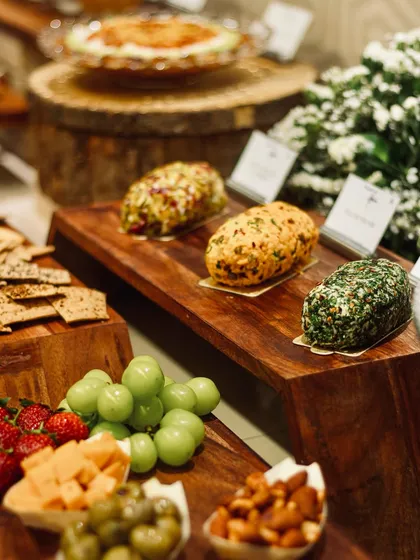 A trio of my artisanal cheese logs on a rustic wooden board, surrounded by fresh grapes and crackers. This is the foundation of a perfect grazing experience.
