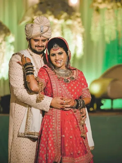 This couple chose a beautiful red lehenga paired with a cream sherwani. The black bangles on the bride add a unique touch, showing how our rental outfits can be personalized with your own accessories.