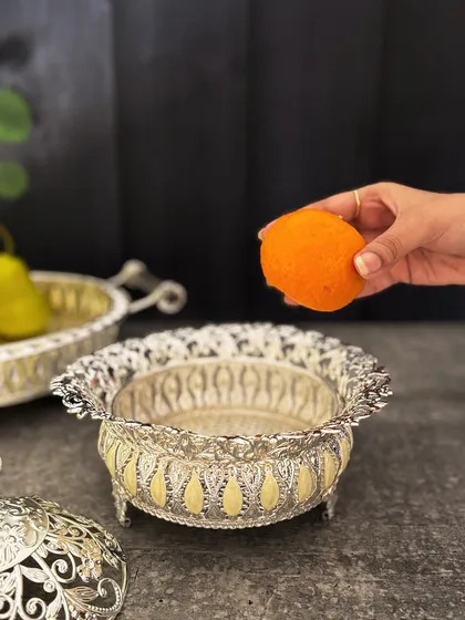 The bowl is shown in use, perfect for serving traditional sweets like laddoos. The elegant design elevates the presentation of any delicacy.