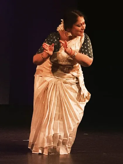 A full-stage view of a performance, showing the dancer's command over the space and the graceful flow of the Mohiniyattam costume.