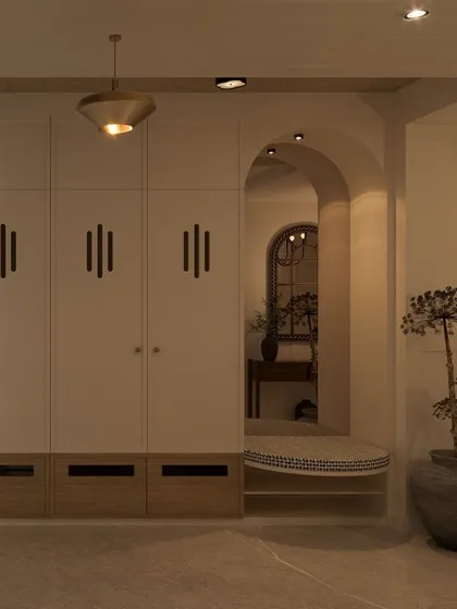 This foyer design combines practical storage with an elegant seating nook set within an arch. The custom handles on the shoe cabinet add a unique, handcrafted detail.