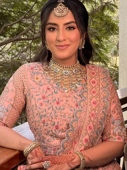 A beautiful pastel bridal look with soft waves and a simple twist, perfect for a daytime wedding. The hairstyle complements the delicate embroidery of the lehenga.