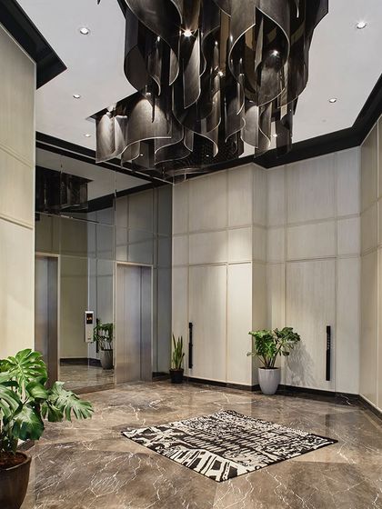 A view of the elevator bay, where the wavy glass light fixture continues, leading residents through the elegantly designed common space.