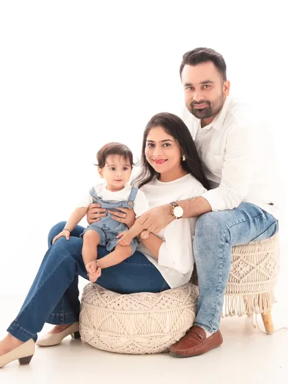 A casual and modern family portrait. Dressed in coordinated white and denim, the family looks relaxed and happy against the clean, minimalist backdrop.