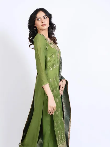 A model showcasing an elegant green ethnic outfit. Her dewy makeup and soft curls complement the traditional attire, making it suitable for brand lookbooks.