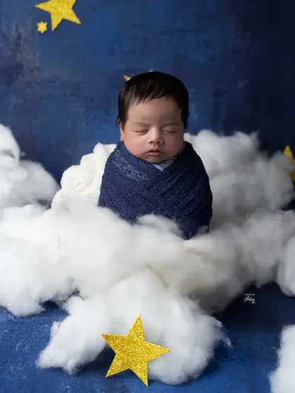 A closer view of the little star, wrapped in a deep blue swaddle and nestled among the soft, cotton clouds.