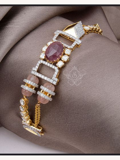 A luxurious diamond bracelet featuring a large central ruby and pink beads. The geometric design of the diamond-studded links adds a modern, architectural feel to this statement piece.