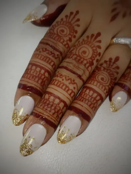 A close-up of the gold foil and white bridal nails, showing how they beautifully contrast with the rich color of the wedding henna.