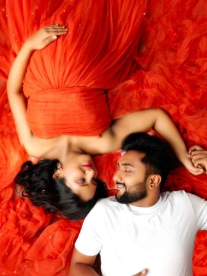 An intimate overhead shot of a couple lying in a sea of red fabric, a truly artistic and romantic way to capture your love story.