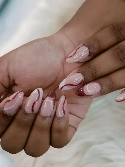 A full hand view of the abstract red and white swirl nails.