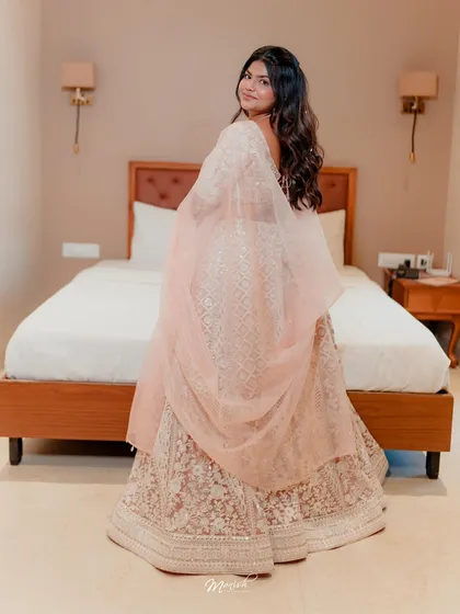A full-length view of this lovely engagement bride. The soft pink lehenga is complemented by a rosy, glowing makeup look and a simple, elegant hairstyle.
