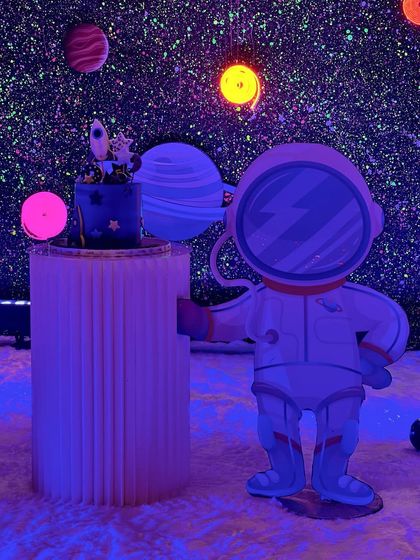 A final look at the astronaut prop and cake, showcasing the vibrant colors of the planets under the party lights.