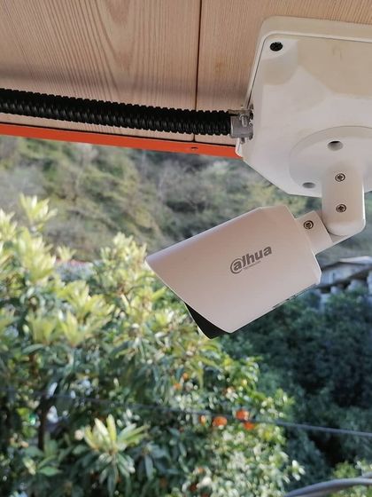 A Dahua bullet camera installed under an eave, protecting it from direct rain while monitoring the surrounding area.