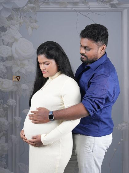 A relaxed and happy portrait of an expecting couple. Their casual outfits and natural poses against a floral backdrop create a comfortable and authentic feel.