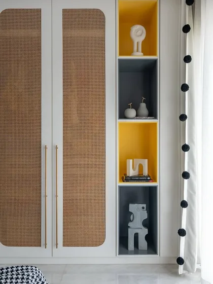 This bedroom wardrobe features custom rattan panels and integrated shelving with pops of yellow. It's a playful and functional design that adds texture and personality to the space.