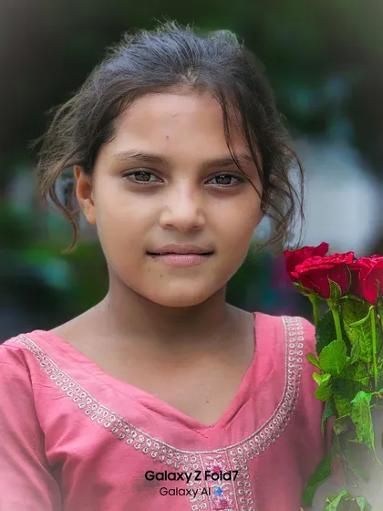 A striking close up portrait of a young girl holding roses. Her soulful eyes and direct gaze make this a powerful and memorable image that tells a story.