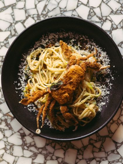 My Spicy Fried Soft Shell Crab Linguine, seen from above. The contrast of the dark bowl and the light-colored pasta makes for a stunning presentation. It's a dish that's as beautiful as it is delicious.
