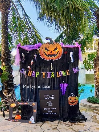 A spooky and fun Halloween-themed photo booth. We set this up by the pool with a black curtain backdrop, a giant pumpkin balloon, and plenty of spooky props for photos.