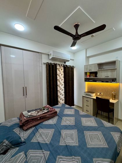 This bedroom combines a light-colored wardrobe with vertical grooves and a compact study unit, creating a functional and cohesive space.