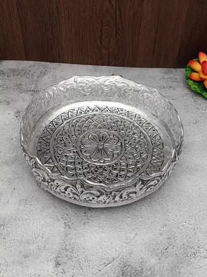 A clear, top-down view of the antique German silver urli with a floral mandala design.