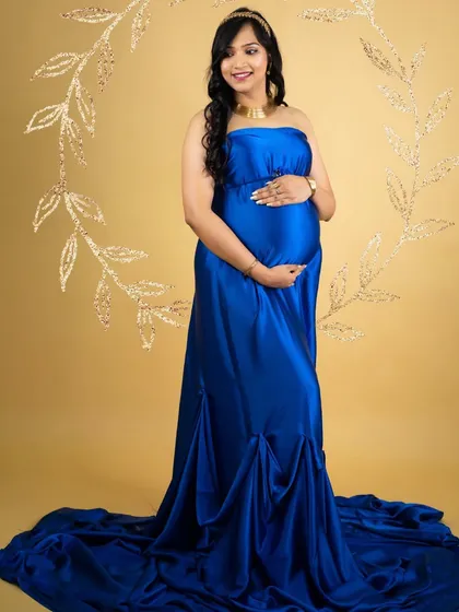 A classic and elegant portrait in a royal blue satin gown. The simple gold background and floral wreath prop add a touch of sophistication.
