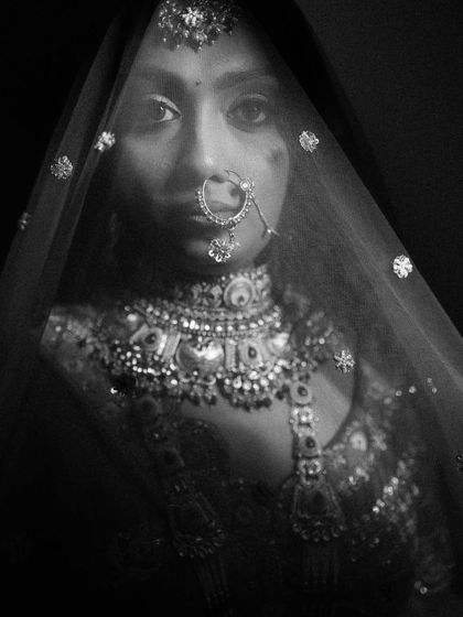 A powerful black and white close-up of a bride looking through her veil. The dramatic lighting and her intense gaze make this a captivating and artistic portrait.