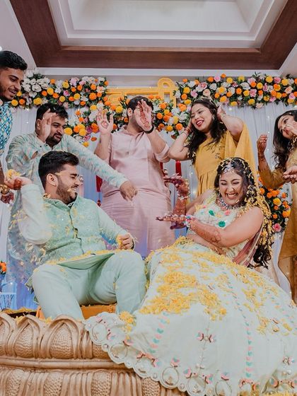 The couple being playfully surrounded by their friends during the Haldi ceremony. A moment of shared joy and friendship.