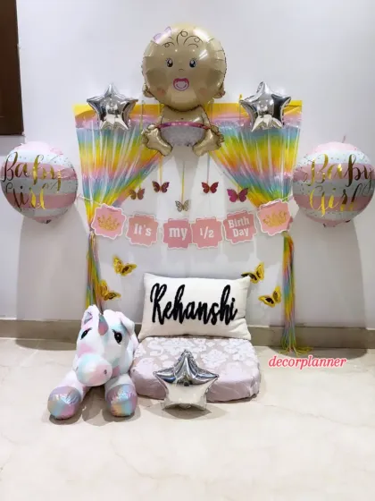 The complete setup for baby Rehanshi's half-birthday. The decor includes a personalized cushion, a cute unicorn plushie, and a 'Baby Girl' foil balloon, making it a perfect little photo corner.