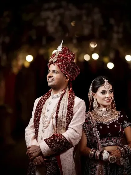 A classic portrait of the bride and groom looking towards the future together. The dark, moody lighting with soft background bokeh creates a dramatic and cinematic feel, emphasizing them as the center of the story.