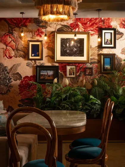 At Echoes, every detail contributes to the story. A bold floral tapestry serves as a backdrop for a curated collection of framed art, creating a rich, layered wall. This maximalist approach feels personal and lived-in, turning a simple dining corner into a conversation piece.