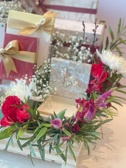 Another angle of our indulgent chocolate hamper, highlighting the lush floral arrangement of red carnations and white chrysanthemums that frames the gifts.
