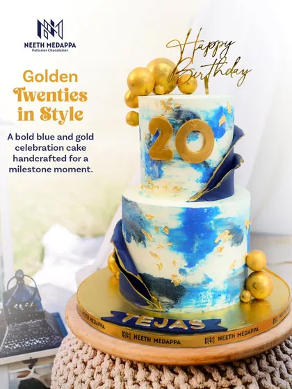 Entering a new decade calls for a cake that makes a statement. This two-tiered 20th birthday cake features a modern blue and white watercolor effect, accented with edible gold leaf, dramatic navy blue sails, and shimmering golden chocolate spheres for a touch of luxury.