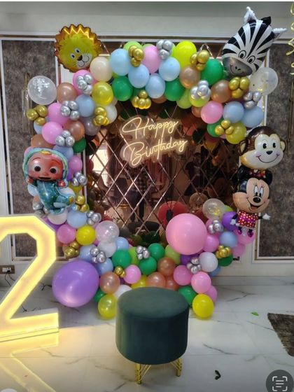 A colorful and fun setup for a second birthday, featuring characters like Cocomelon and Mickey Mouse, a light-up number '2', and a multi-colored balloon ring.