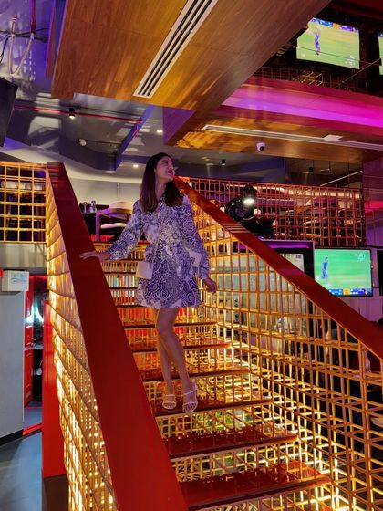 A fun, printed dress for a night out at a restaurant with vibrant, modern decor. The colorful stairs and lighting make the perfect backdrop for a playful outfit.
