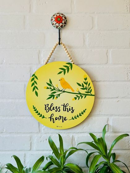 Our 'Bless This Home' wooden sign, featuring a hand-painted yellow bird on a branch. This 12-inch round sign is a beautiful way to add a touch of nature and positivity to your entrance.