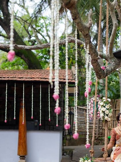 A couple on the swing, surrounded by hanging floral decorations, creates a whimsical and romantic scene.
