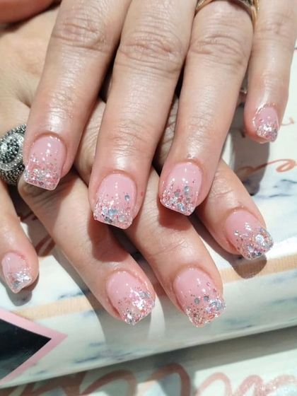 A subtle yet sparkly look on short, natural nails, featuring a sheer pink base with a delicate silver glitter gradient on the tips.