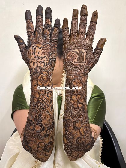 This bridal design features the groom's initial 'R' on one palm and a meaningful phrase in Arabic on the other.