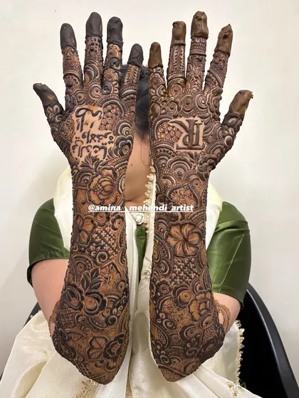 This bridal design features the groom's initial 'R' on one palm and a meaningful phrase in Arabic on the other.