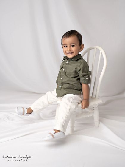 A happy little boy in a simple, classic studio setup for his milestone portrait.