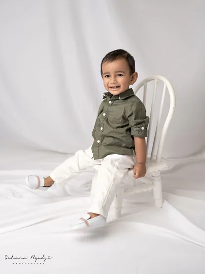 A happy little boy in a simple, classic studio setup for his milestone portrait.