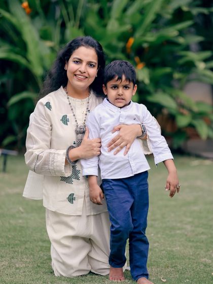 A mother kneels to embrace her son in a garden setting. This pose creates a sense of intimacy and connection, perfect for a parent-child portrait.