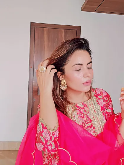 This image showcases the details of the pink floral suit, from the delicate sleeve embroidery to the pairing of a statement ring and traditional earrings.