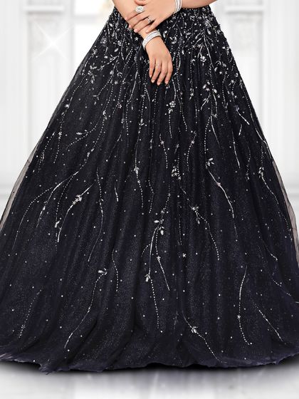 A detailed look at the flowy tulle skirt of our black reception gown, which is covered in delicate, light-catching embellishments.