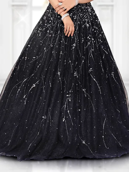A detailed look at the flowy tulle skirt of our black reception gown, which is covered in delicate, light-catching embellishments.