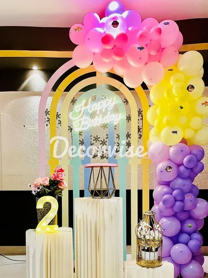 This setup demonstrates how we use color and light to create a vibrant party atmosphere. A pastel rainbow backdrop is accented with a neon "Happy Birthday" sign and a multi-colored balloon garland.