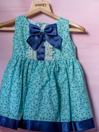 A lovely turquoise printed dress with delicate white lace applique and a large navy blue satin bow at the neckline. It's a beautiful combination of color and texture.