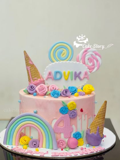 A pastel-colored cake for Advika's 4th birthday. This pretty cake is decorated with a rainbow, ice cream cones, lollipops, and delicate floral details.