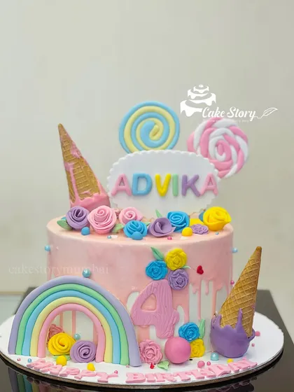 A pastel dream cake loaded with sweet treats. This design features a rainbow, ice cream cones, and lollipops, making it a perfect candy-themed cake for a 4th or 5th birthday.