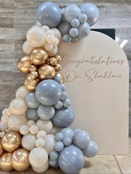 An elegant congratulatory setup for a new doctor. The balloon arrangement in dusty blue, white, and gold offers a sophisticated and celebratory feel.